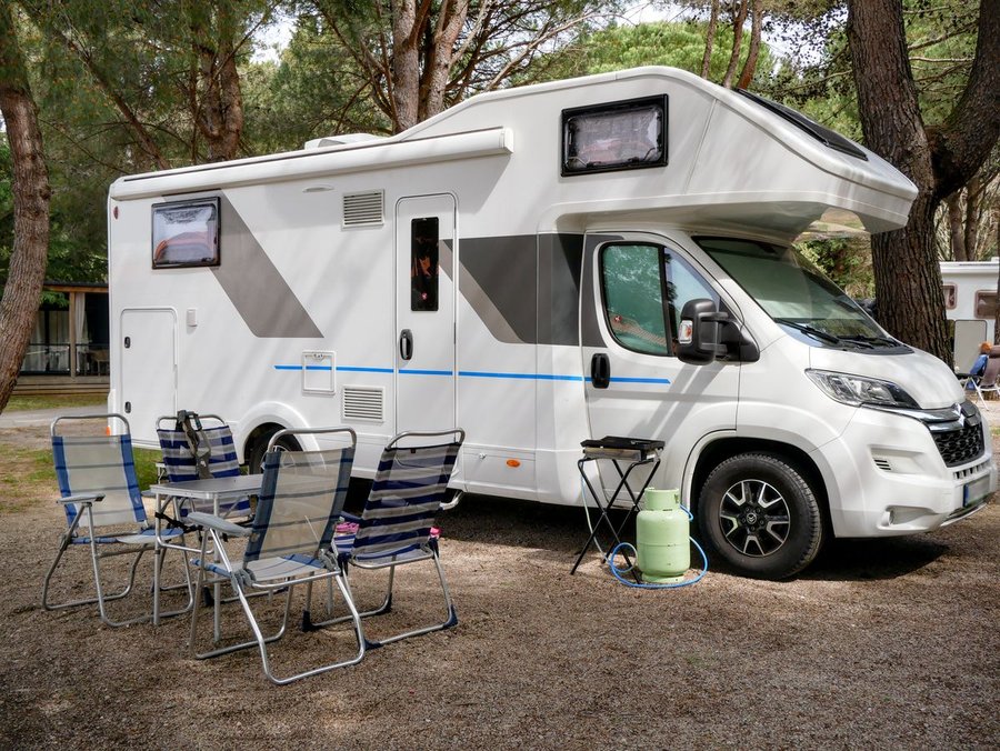 Illustrative sample photo: white coachbuilt motorhome with over-cab bed, parked at a wooded campsite. Not the actual vehicle.